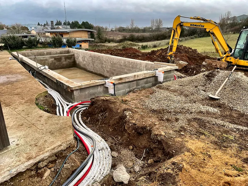 Chantier de construction – Pose des réseaux hydrauliques autour du bassin en agglo.
