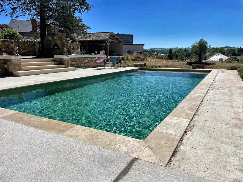 Rénovation de piscine – PVC armé sable, margelles claires et vue sur la campagne.