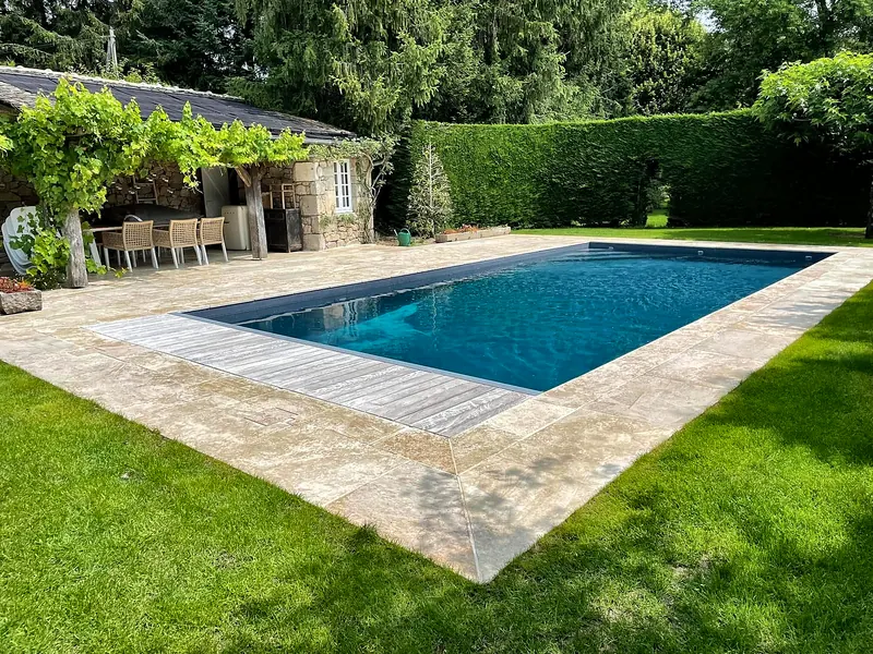 Rénovation de piscine – Plage en pierre naturelle, volet immergé et pool house.