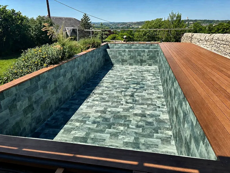 Rénovation de piscine – PVC armé imitation pierre et terrasse en bois.