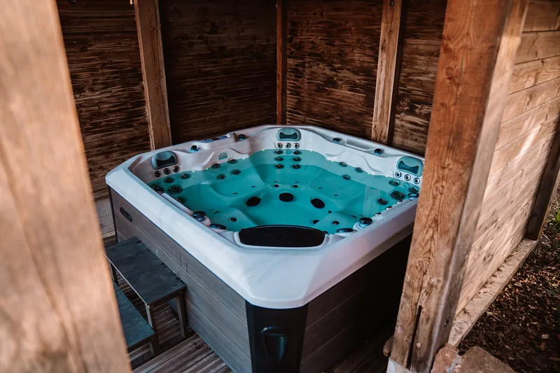 Spa sous abri bois – Spa encastré dans un abri en bois, avec marche d’accès.