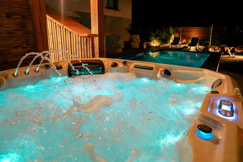 Spa et piscine de nuit – Fontaines, éclairage LED et piscine en arrière-plan.